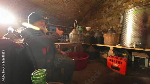 4k time lapse of old caucasian man draining and bottling wine in home cellar video footage photo