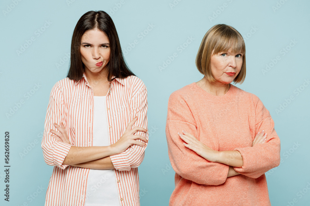 Sad offended miffed elder parent mom with young adult daughter two women together wear casual clothes hold hands crossed folded look camera isolated on plain blue cyan background. Family day concept. - obrazy, fototapety, plakaty 