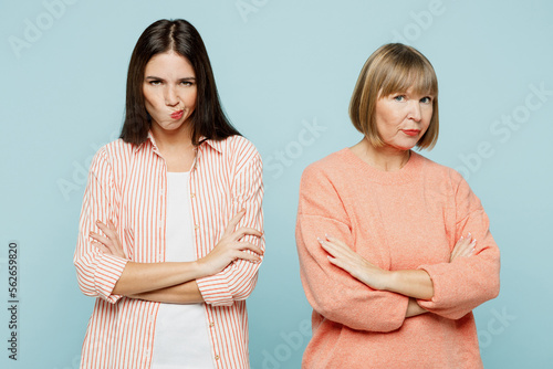 Sad offended miffed elder parent mom with young adult daughter two women together wear casual clothes hold hands crossed folded look camera isolated on plain blue cyan background. Family day concept.