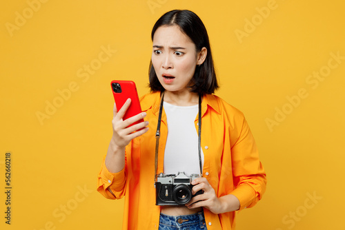 Young shocked sad woman in summer casual clothes hold use mobile cell phone isolated on plain yellow background. Tourist travel abroad in free spare time rest getaway Air flight trip journey concept #562660218