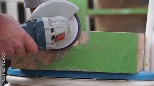 Artigiano a lavoro, mentre scartavetra un cassetto di legno con una smerigliatrice angolare photo