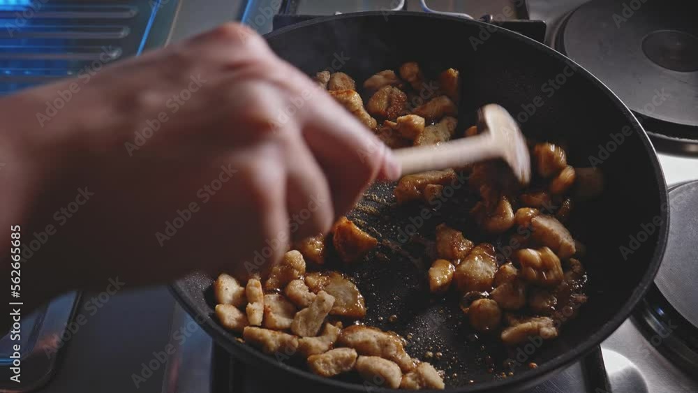Cooking And Stirring Chopped Chicken Breast In A Skillet With Honey And Soy Sauce. closeup Cooking And Stirring Chopped Chicken Breast In A Skillet With Honey And Soy Sauce. closeup