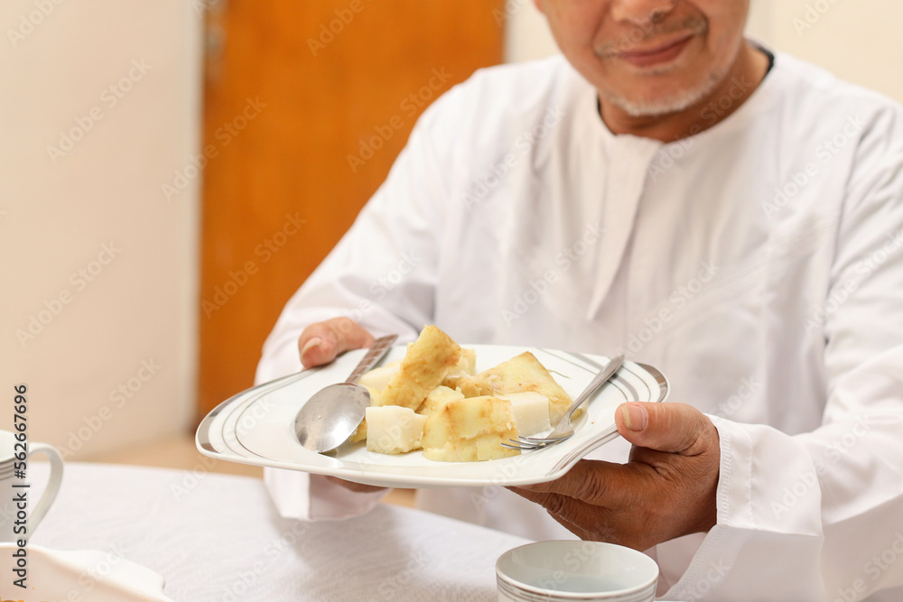 Asian muslim man showing ketupat on plate, ready to eat food on Eid Mubarak ramadan celebration at dining room Asian muslim man showing ketupat on plate, ready to eat food on Eid Mubarak ramadan celebration at dining room