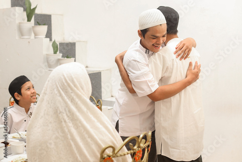 Brother greeting each other with hugging during the Eid Mubarak ramadan celebration at dining room. photo