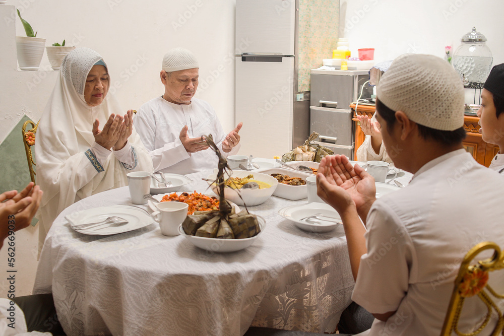 Muslim family are praying together before eat special dish on eid moment, hand raised and bow head. Eid Mubarak ramadan celebration. Muslim family are praying together before eat special dish on eid moment, hand raised and bow head. Eid Mubarak ramadan celebration.