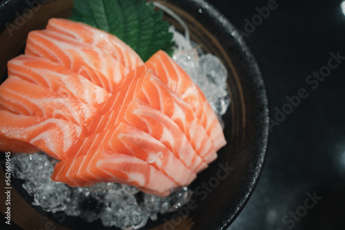 Close up of a raw salmon slice of salmon sashimi served on ice in a bowl