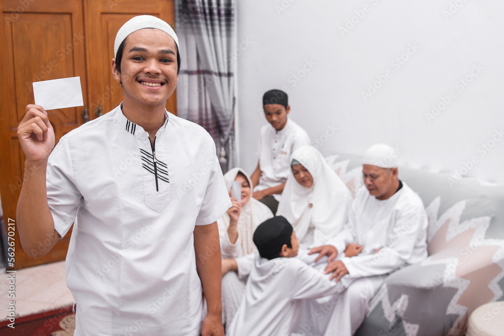 Smiling young muslim boy showing envelope as a gift from the Eid Mubarak ramadan celebration. 