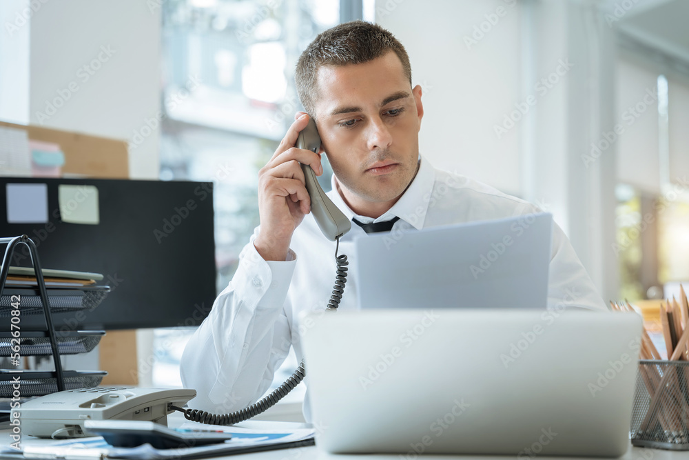 Asian Businessman sitting in office using a cellphone and laptop. Asian Businessman sitting in office using a cellphone and laptop.