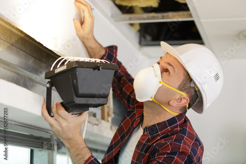 Cuadro en lienzo contractor using a lamp to inspect roof area