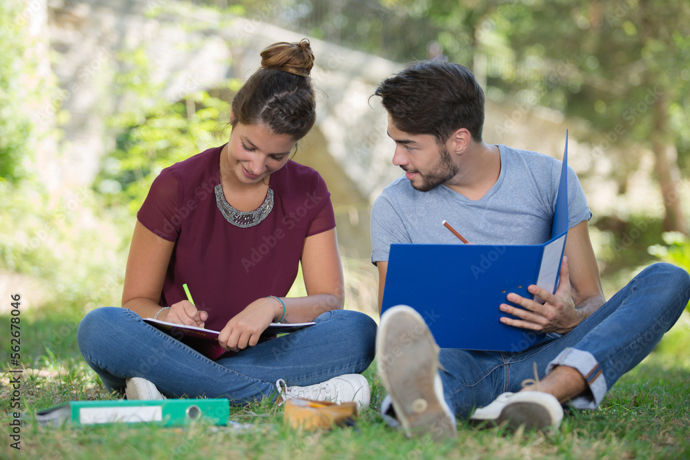 couple of students with a notebook outdoors couple of students with a notebook outdoors