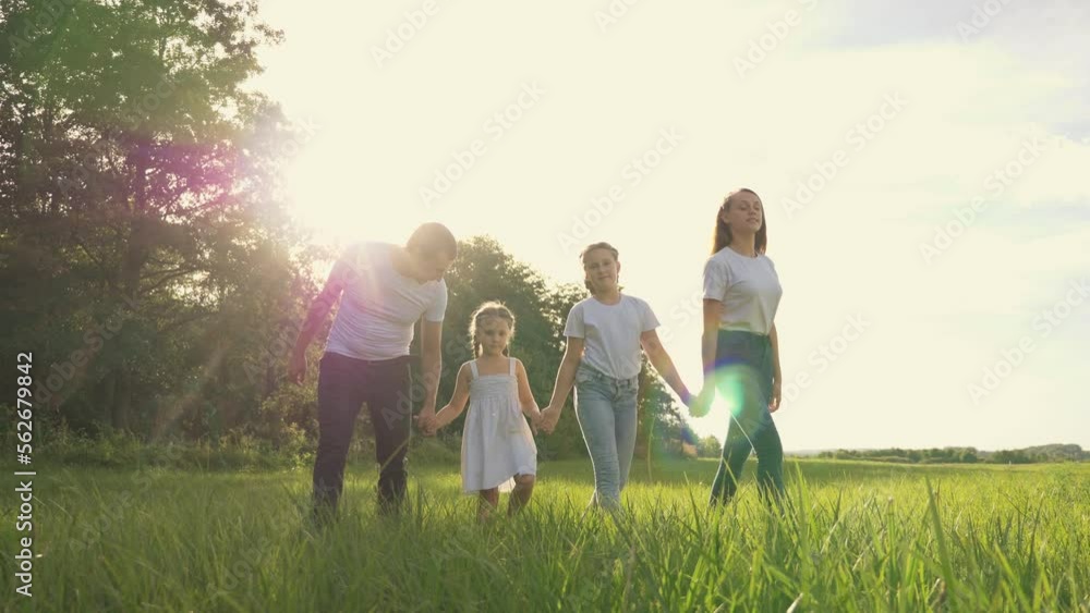 Happy family in park at sunset. mother, father,children girls walk in park at sunset together outdoors on green nature. concept of happy family in nature, parenting, adoption of children, walk in park Happy family in park at sunset. mother, father,children girls walk in park at sunset together outdoors on green nature. concept of happy family in nature, parenting, adoption of children, walk in park