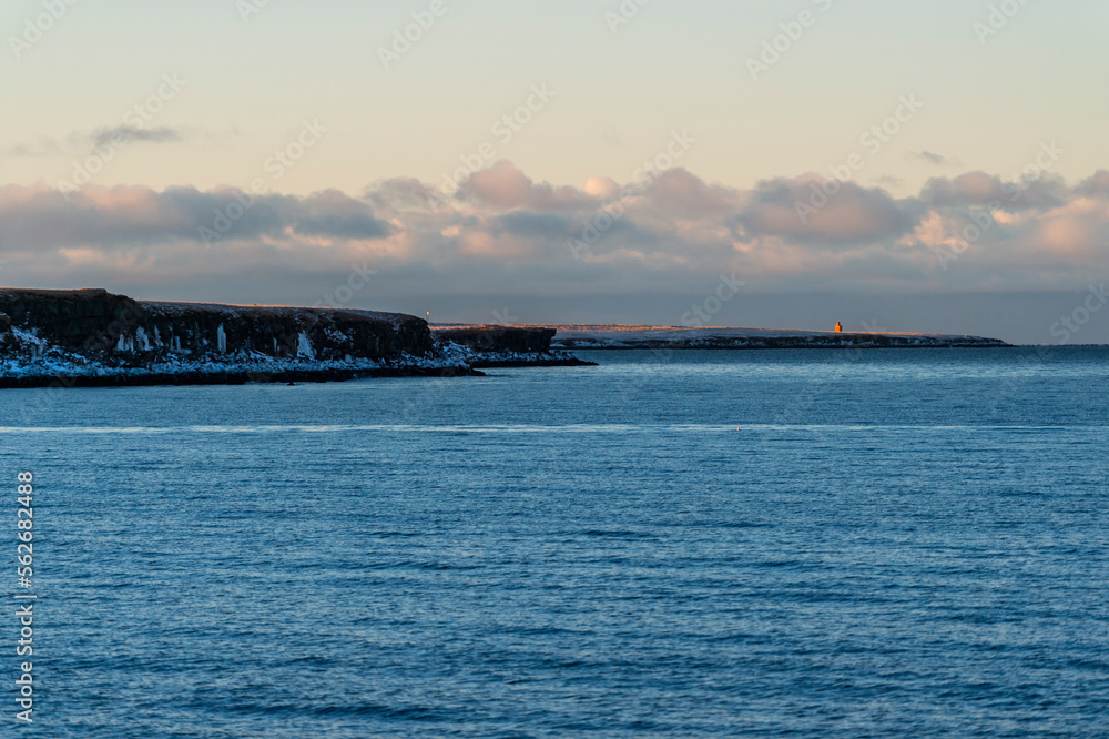 imagen de la línea de costa des del mar con el cielo azul y algunas nubes 