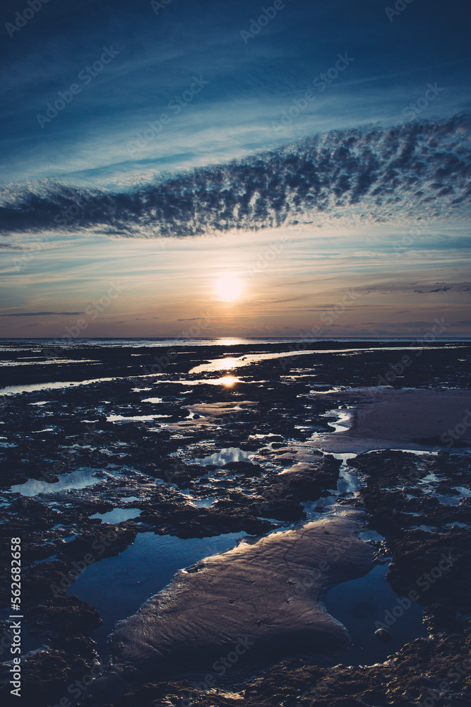un coucher de soleil dans un ciel bleu sur la plage à marée basse