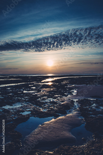 un coucher de soleil dans un ciel bleu sur la plage à marée basse