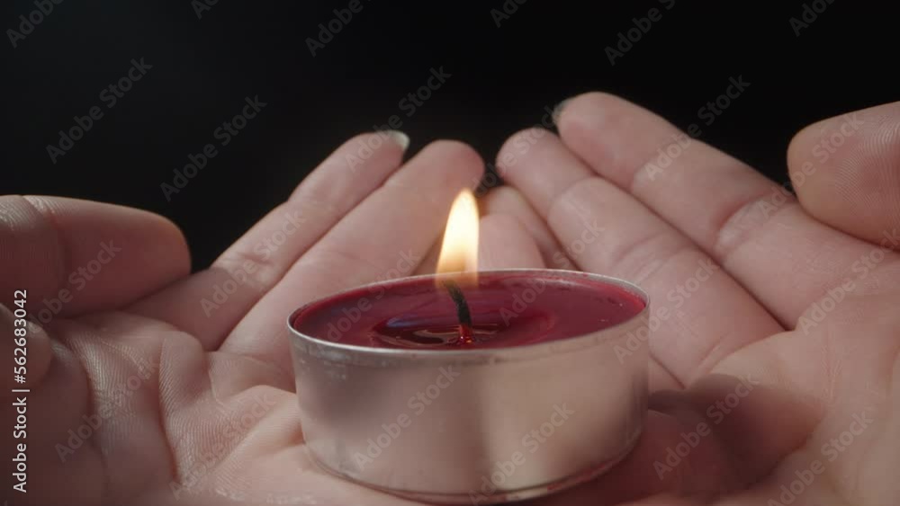 I light a red candle in the girl's palms, close-up. I light a red candle in the girl's palms, close-up.