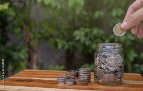 coin saving hand on wooden table and natural background saving money for future retirement or investment