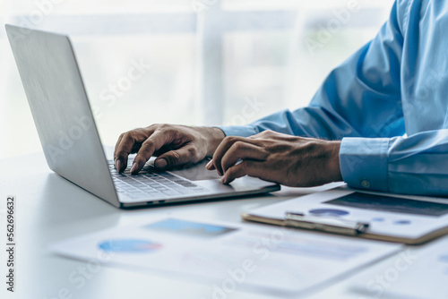  Businessman hands on keyboard of laptop computer showing data analysis graph Businessman working and analyzing financial figures on graph document