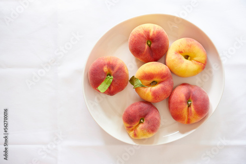 Overhead view of peaches in plate over white background photo