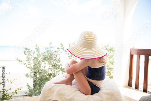 Girl wearing hat and swimwear while hugging her knees