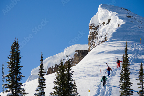 Group of three skiers hiking up boundary line at ski area.