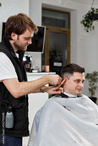 Barber shaving caucasian man in barber shop.
