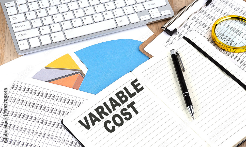 VARIABLE COST text on notebook with chart and keyboard VARIABLE COST text on notebook with chart and keyboard