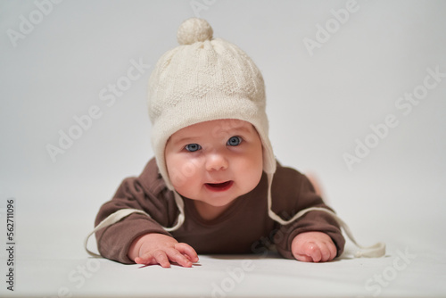 portrait of a smiling baby on a light background in a warm knitted white hat