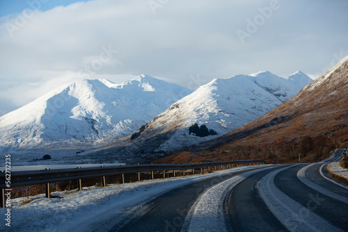 An empty road travelling towards snow covered mountains in Scotland.