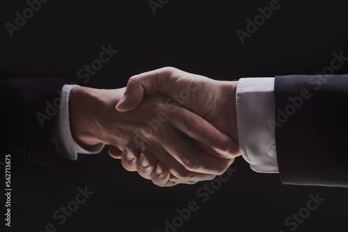Photo of two men in suits shaking hands on a black background
