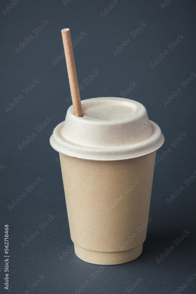 Coffee in a disposable paper cup with a straw on a gray background. Unbranded recycled paper cup with a copy space for a free text. Mockup. Care for the environment. Recycling or eco-friendly concept Coffee in a disposable paper cup with a straw on a gray background. Unbranded recycled paper cup with a copy space for a free text. Mockup. Care for the environment. Recycling or eco-friendly concept