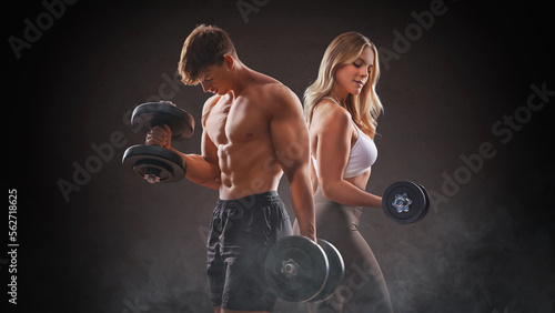  smiling woman an man with dumbbell - successful fitness studio concept