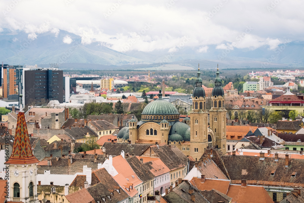 Aerial cityscape of historic Sibiu city in Transilvania, Romania, and cloudy Carpathian mountains
