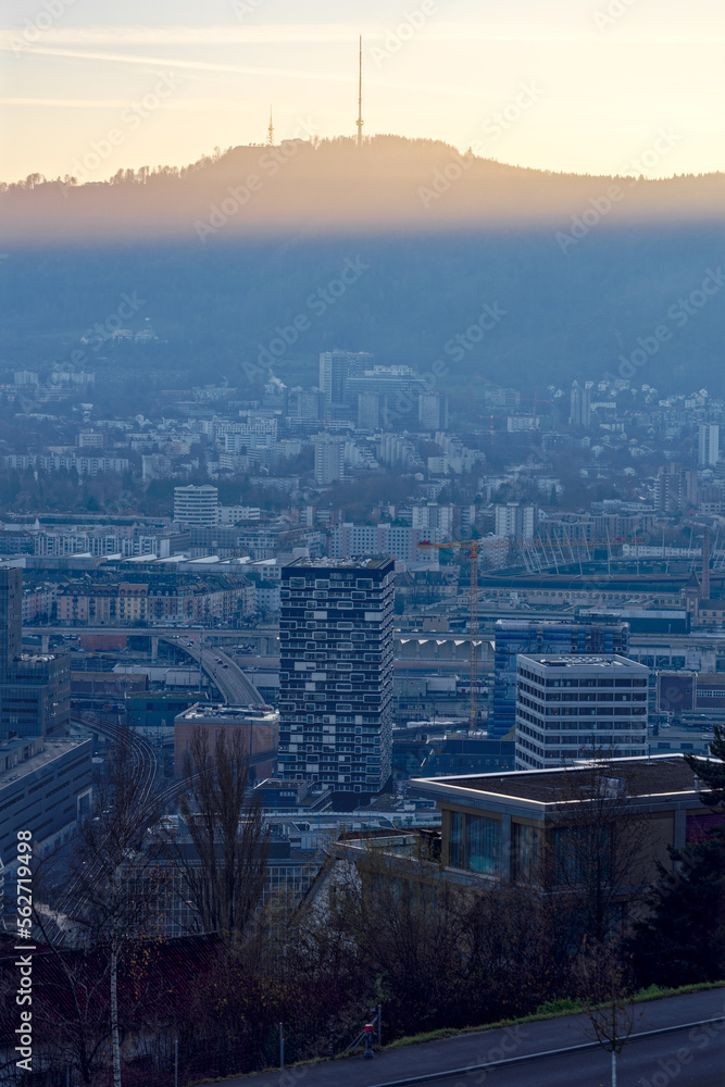 Aerial view over city of Zürich with local mountain Uetliberg in the background and bright sunlight and beautiful autumn evening sun. Photo taken December 6th, 2022, Zurich, Switzerland.