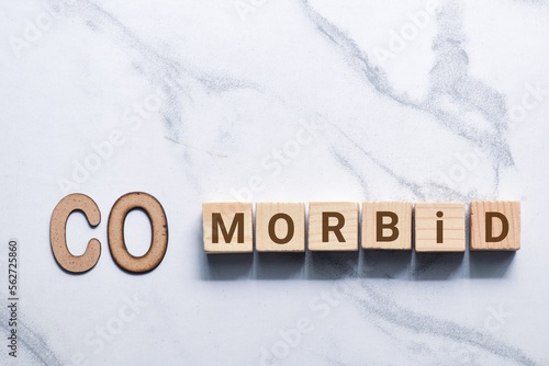 The word COMORBID in wooden letters and blocks on white background. Complex medical condition concept. photo