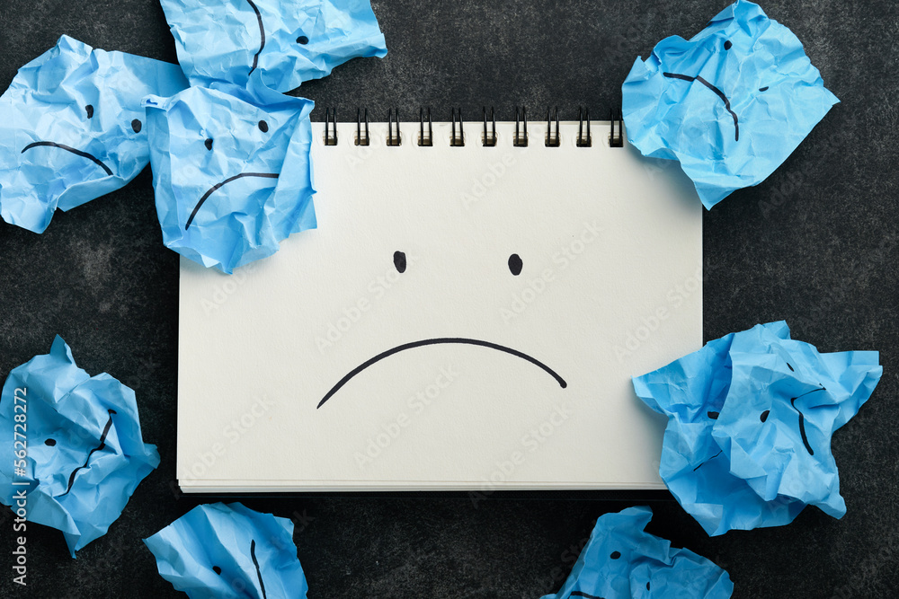 Blue crumpled sticky notes blank with drawing sad face on black ...