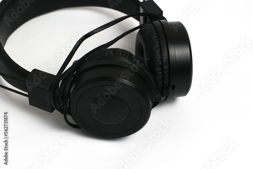 Black headphones with wire on a white background. Cheap headphones for listening to music © queen1987