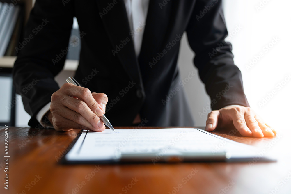 Young Asian legal advisor or lawyer reading financial details investment agreement Signing a contract for validity before the delivery of documents to help his clients succeed. Young Asian legal advisor or lawyer reading financial details investment agreement Signing a contract for validity before the delivery of documents to help his clients succeed.