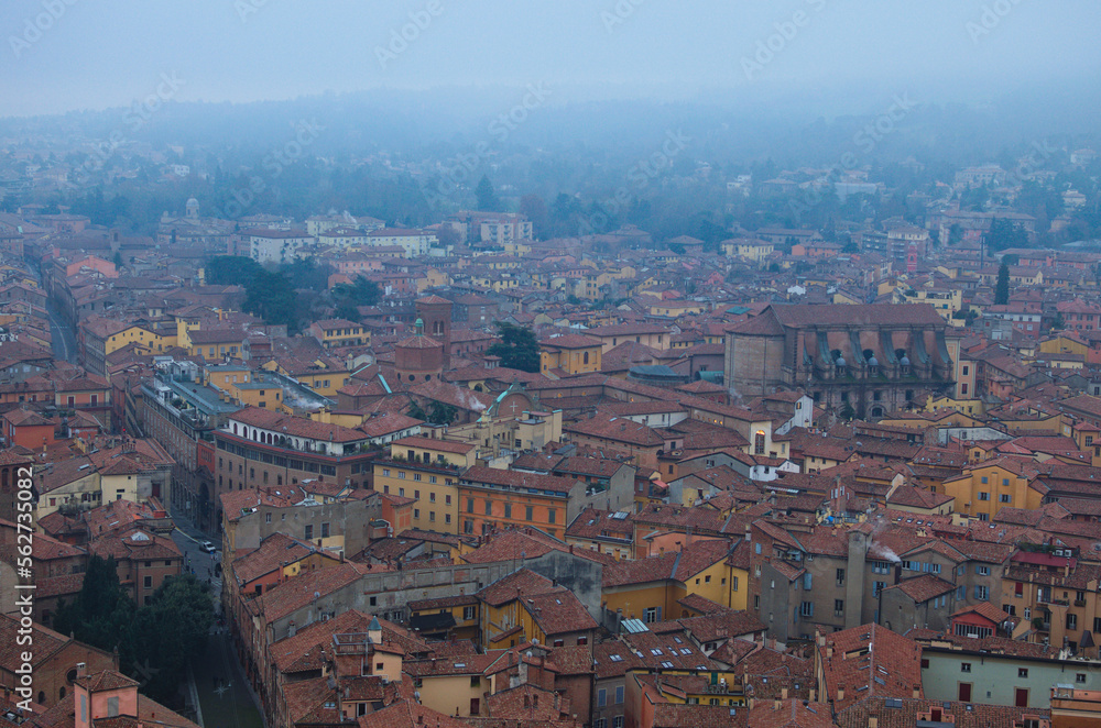Fototapeta premium Scenic bird-eye view from the top of the tower on Bologna old town center. Vintage buildings with red tile roofs. Famous touristic place and travel destination in Europe. UNESCO World Heritage Site
