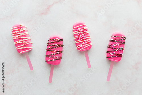 Four bright pink cakesicles for Valentine's day against a light background. photo