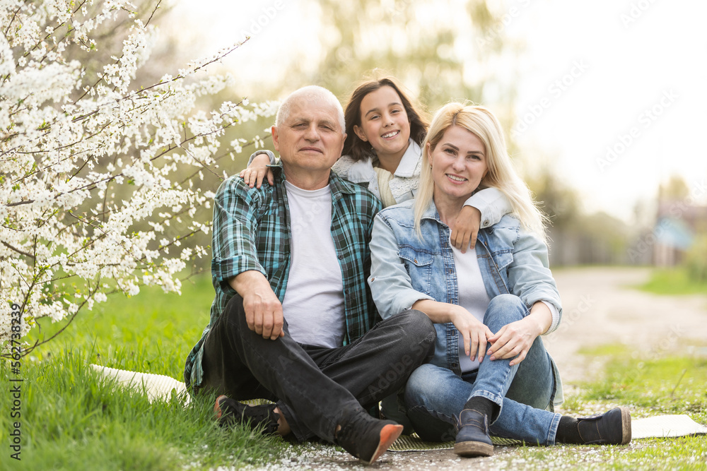 Fototapeta premium Three generation family sitting outside in spring nature