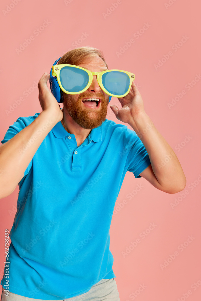 Happy man in casual style clothes and funny huge eyewear with funky facial expression over pink background. Concept of funny meme emotions, happiness, ad, sales. Happy man in casual style clothes and funny huge eyewear with funky facial expression over pink background. Concept of funny meme emotions, happiness, ad, sales.