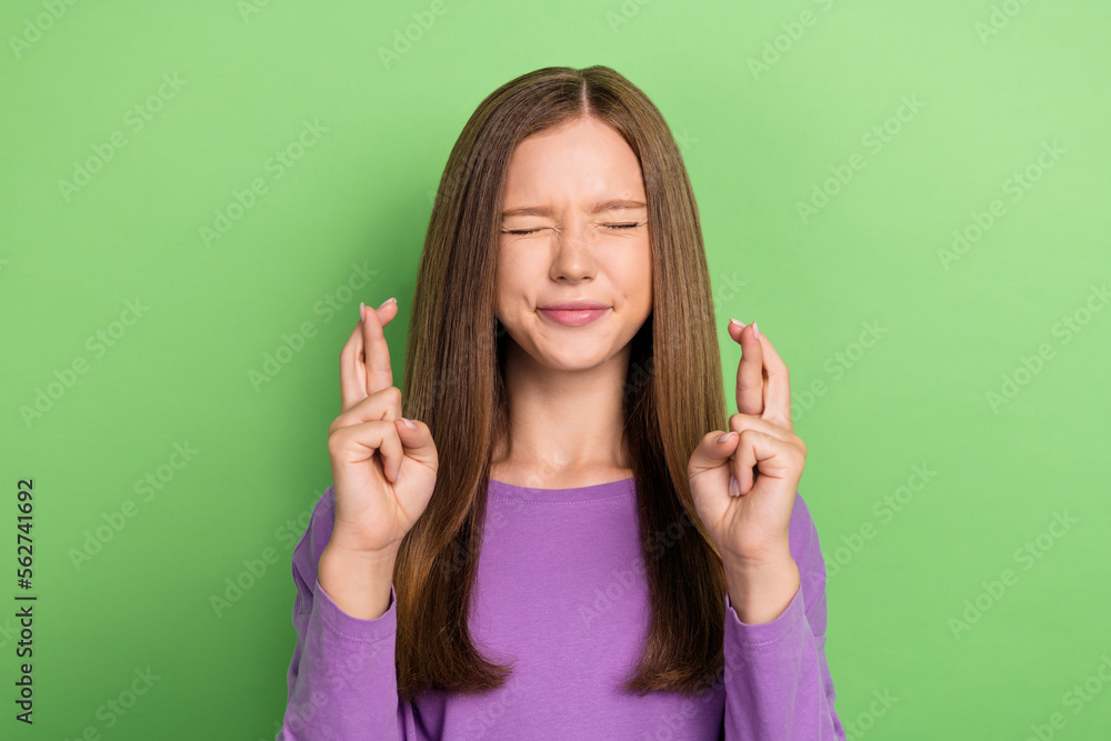 Portrait of nice positive girl long hairstyle wear purple long sleeve fingers crossed eyes closed isolated on green color background Portrait of nice positive girl long hairstyle wear purple long sleeve fingers crossed eyes closed isolated on green color background