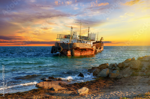 Old cargo ship is aground on the Black Sea coast at sunset in Crimea, Ukraine