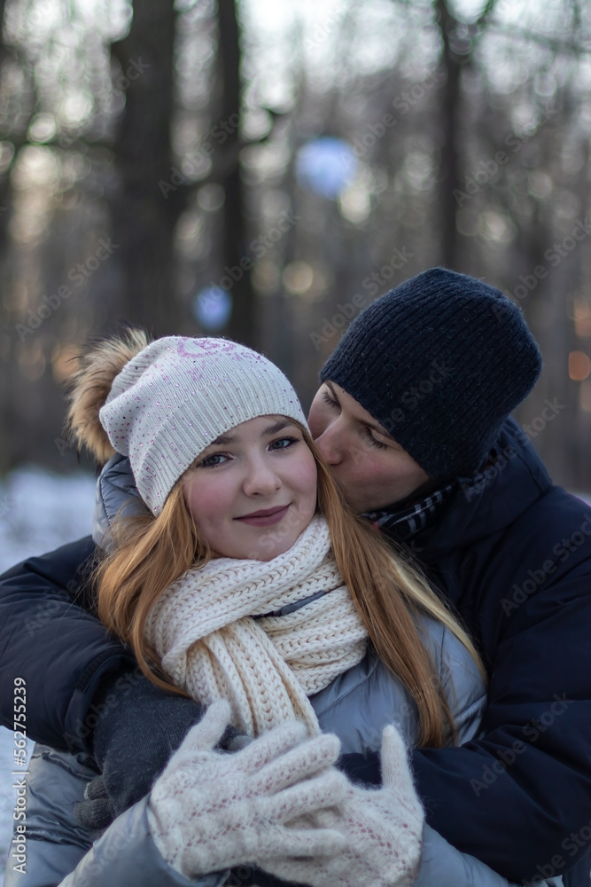 young man kissing his girlfriend in winter park