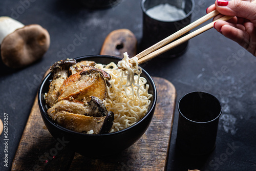 Noodles with eringi mushrooms in a black plate photo