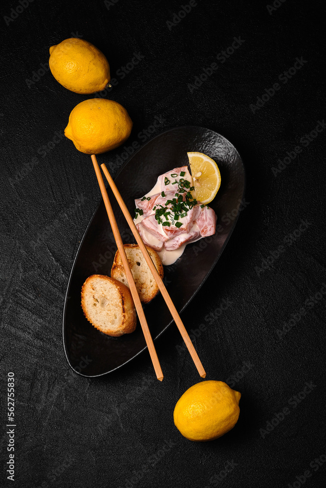 Marinated salmon and toasts on black plate on black concrete background Marinated salmon and toasts on black plate on black concrete background