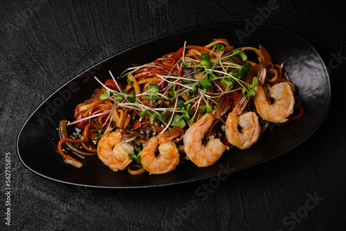 Stir-fried yakisoba noodle with vegetable and shrimps on black concrete background. Asian food style. Top view photo