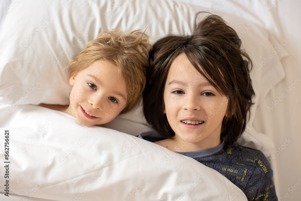 Mother and child, blond toddler boy, cuddling in bed in the morning, love and tenderness Mother and child, blond toddler boy, cuddling in bed in the morning, love and tenderness