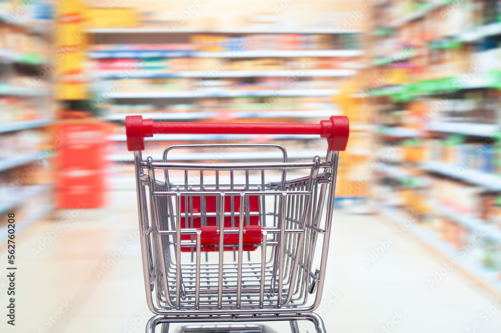 Empty shopping trolley cart on blurring supermarket aisle background