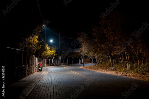 empty brick road at night with lanterns and person on the sidewalk